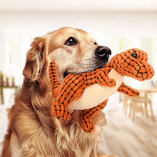Small dog happily chewing on a orange plush dinosaur toy, designed for safe play and teething relief.